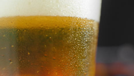 Macro-shot-of-a-beer-glass-with-cold-beer-bubbles-rise-in-the-glass.-Slow-motion-beer-bubbles